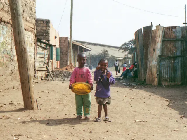 In this image I can see two kids are standing in the middle. At the back side there are trees and...